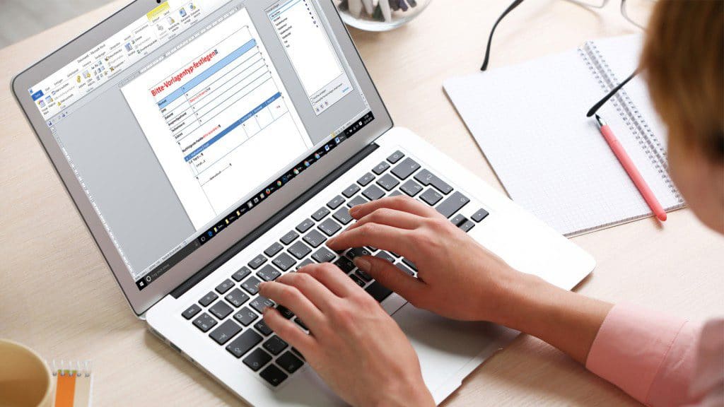 Hände tippen auf einem Laptop mit geöffnetem Word-Dokument
